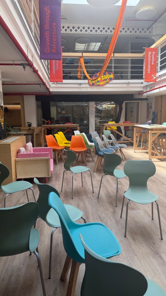 Indoor space with colorful chairs arranged around a wooden table, featuring banners that promote growth and positive relationships.